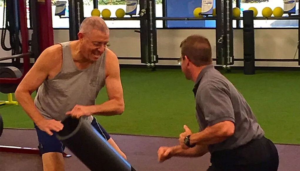 A male personal trainer coaching an older male client