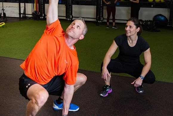 A female personal trainer encouraging a male client during a weight exercise