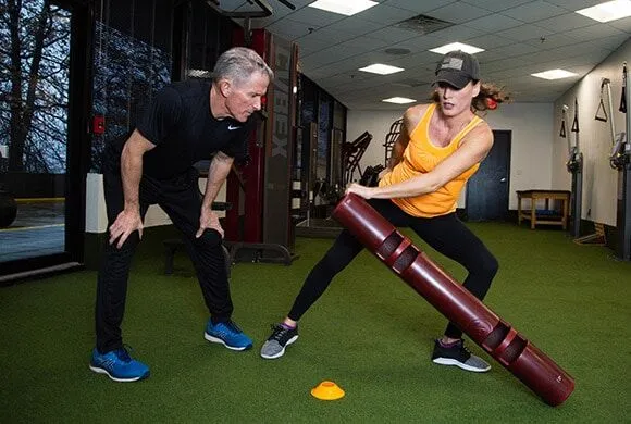 A male personal trainer coaching a female client through a weight exercise