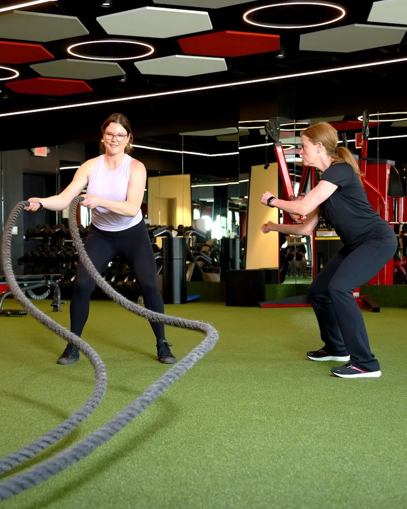 A female personal trainer works with a young woman on arm workouts.