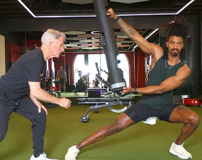 A male personal trainer coaching a male client through a weight exercise
