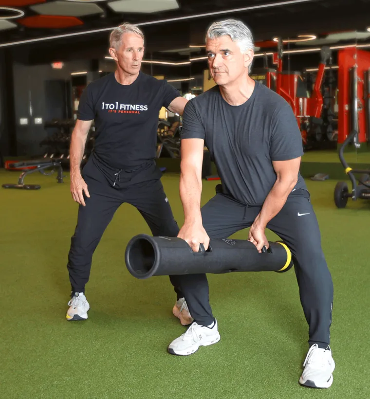A male personal trainer coaches a male client through a weight exercise